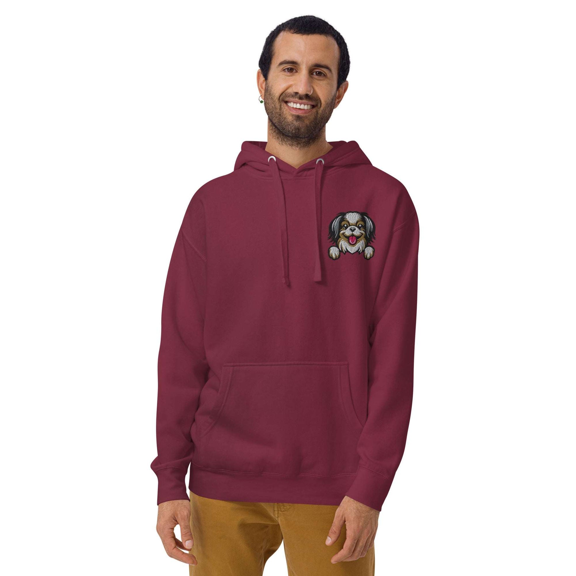 Man wearing maroon premium hoodie with embroidered Japanese Chin dog design on chest and pouch pocket