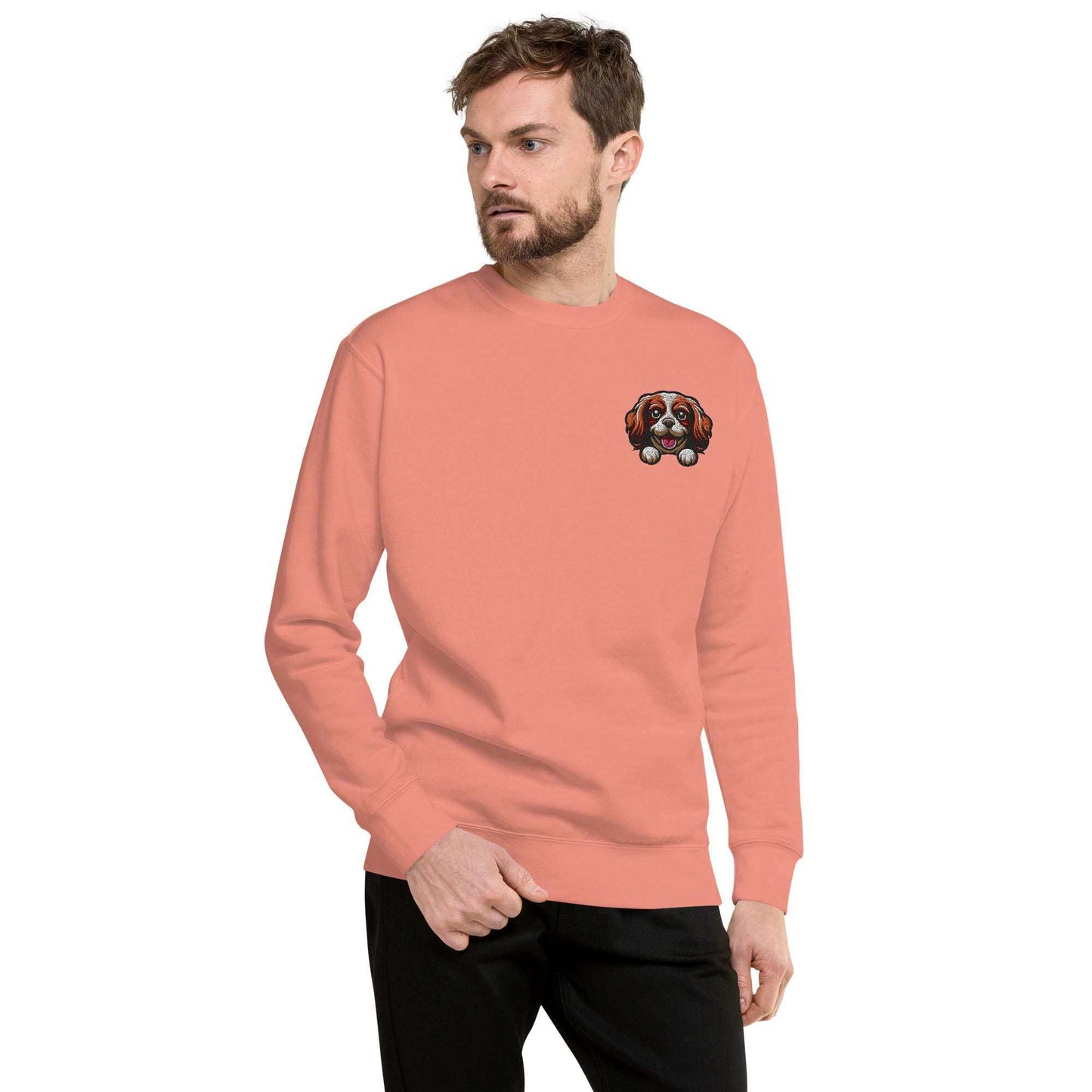 Man wearing coral sweatshirt with embroidered Cavalier King Charles Spaniel dog face on chest