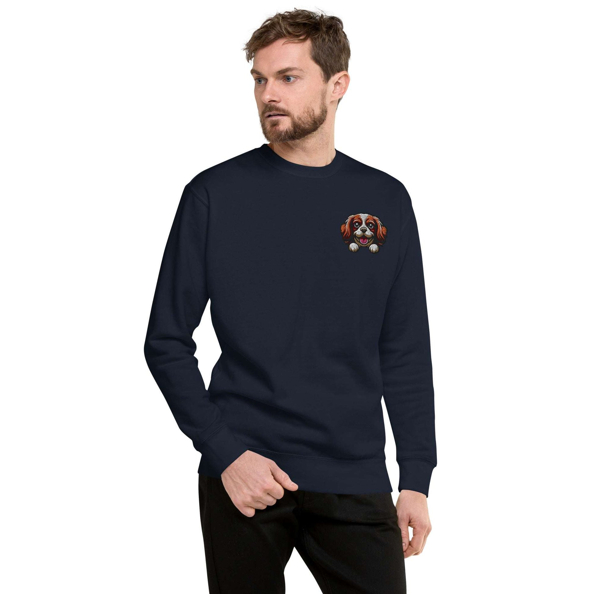 Man wearing a navy sweatshirt with embroidered Cavalier King Charles Spaniel dog face on chest